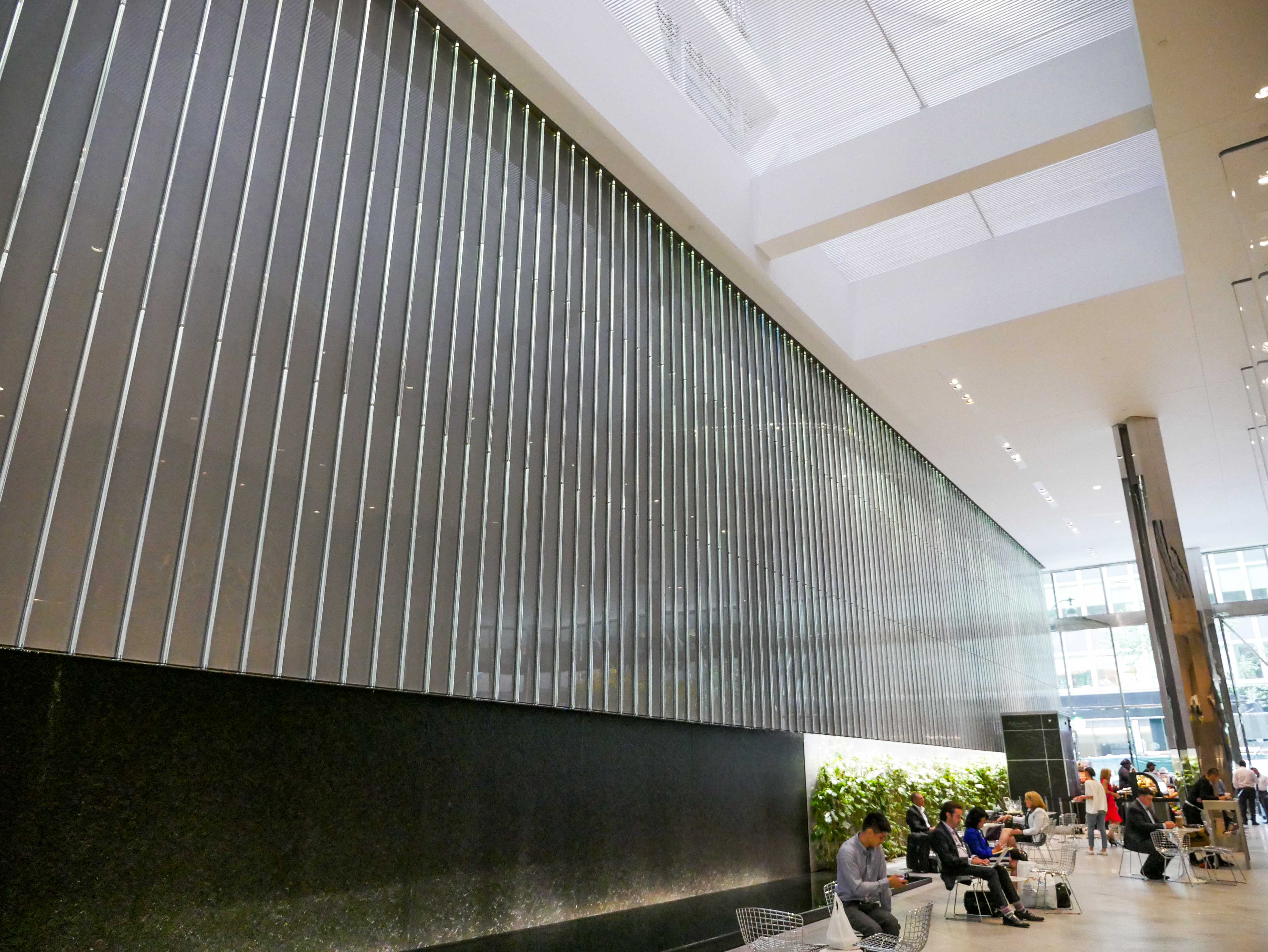 Inside BlackRock's office tower, AGNORA's Park Ave Atrium features big glass with oversize laminate panels with low iron, back painted metallic ceramic frit, with people sitting in the background at the Starbucks cafe.